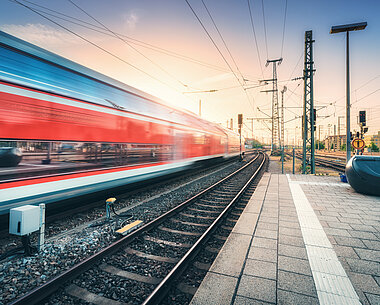 Effectenspiegel-bahn-einfahrt-in-bahnhof-fahrender-roter-zug