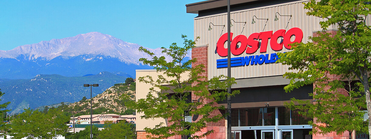 Effectespiegel-costco-großhandel-vor-bergpanorama-rotes auto auf Parkplatz vor gebaeude